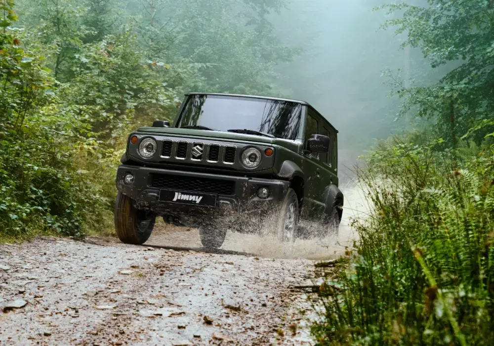 Suzuki Jimny 5 Puertas color verde oscuro atravesando un camino de tierra