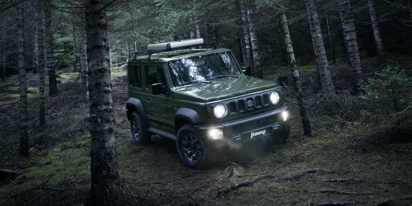 El Suzuki Jimny color verde jungla andando en el medio de un bosque.