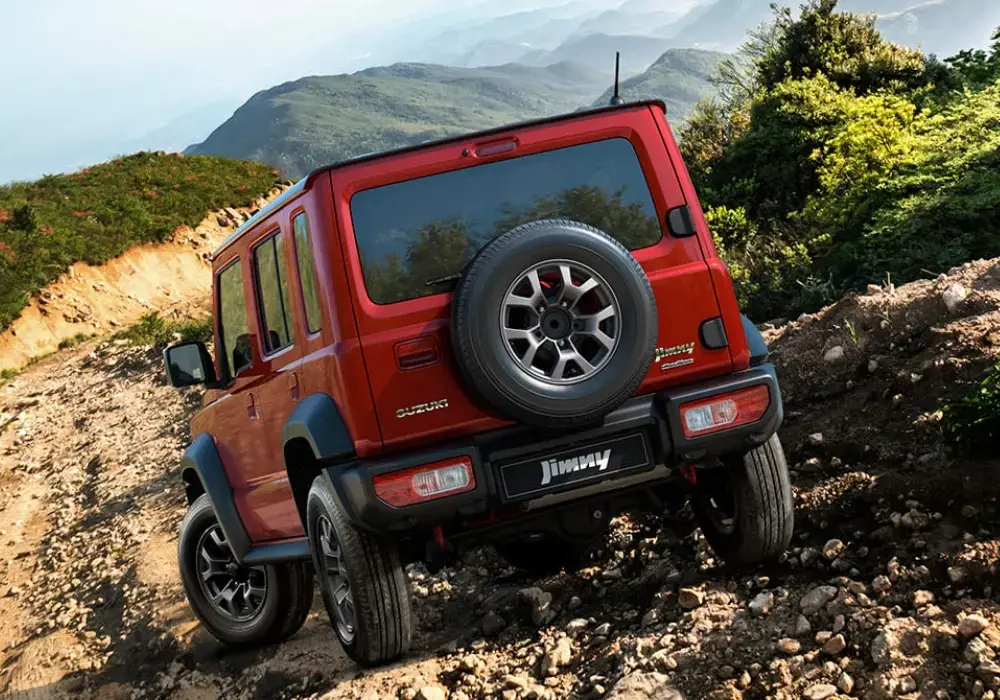 Suzuki Jimny rojo 5 puertas subiendo por un sendero rocoso